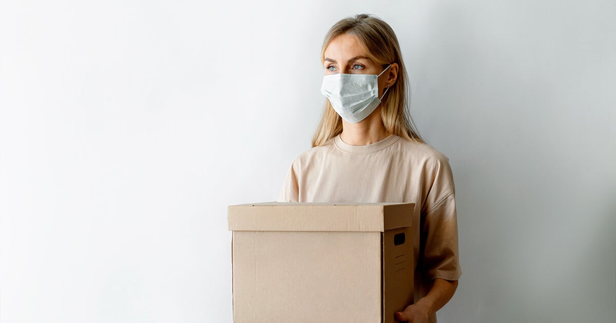 Woman holds boxes with face mask on for Covid-19 protection