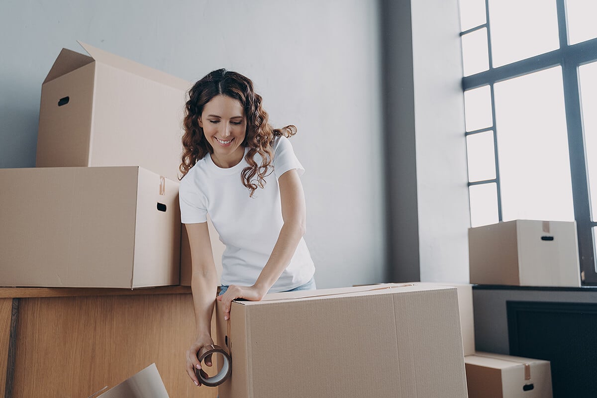 Young woman tapes up boxes ready to be moved into shipping container