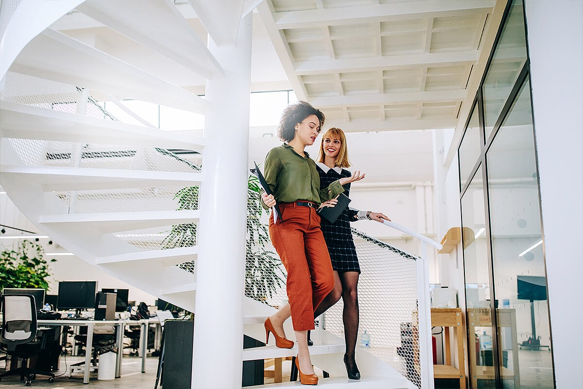 Two business women walk down stairs ready for office relocation