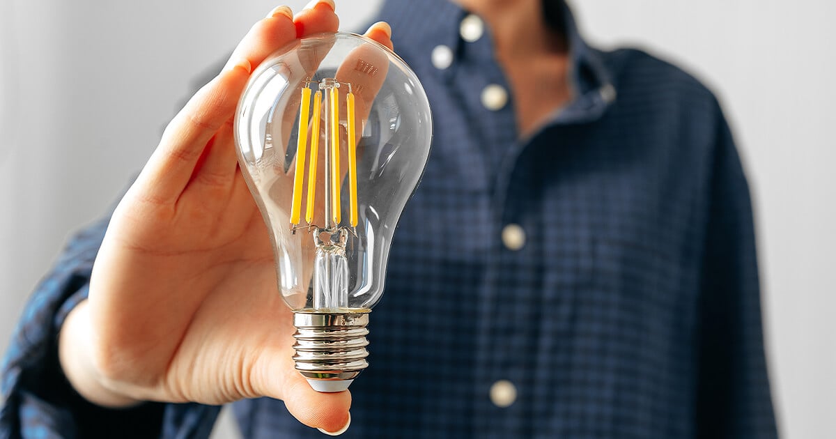 Woman holds up light bulb in front of her ready to instal after moving house