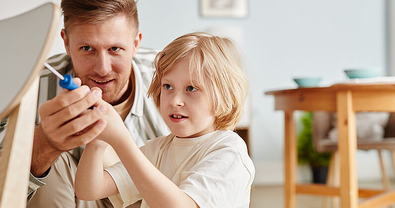 Preparing furniture donations - man and boy fixing chair