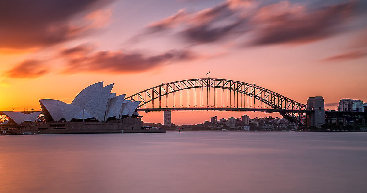 Sunset view of the Sydney Opera House and Sydney Harbour Bridge with orange and pink cloud and sky in background