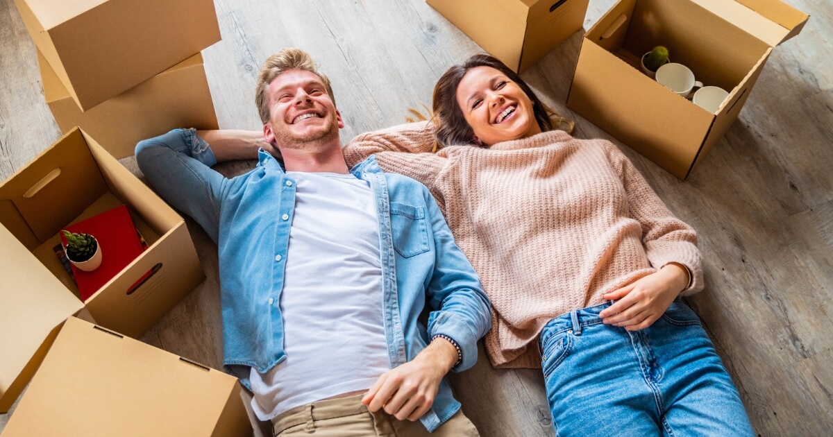 Happy couple lying on the floor surrounded by moving boxes