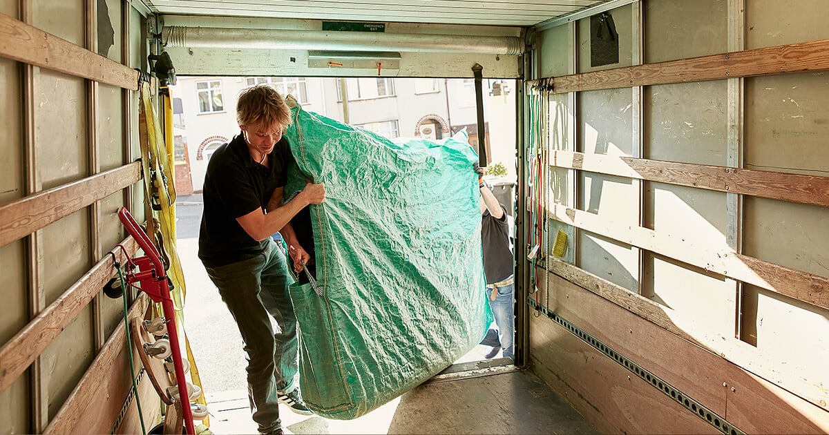 Two movers lift mattress into back of removalist truck for interstate move