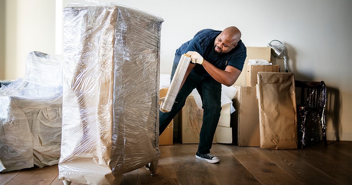 Removalist packing up dresser with packing materials to be shipped interstate