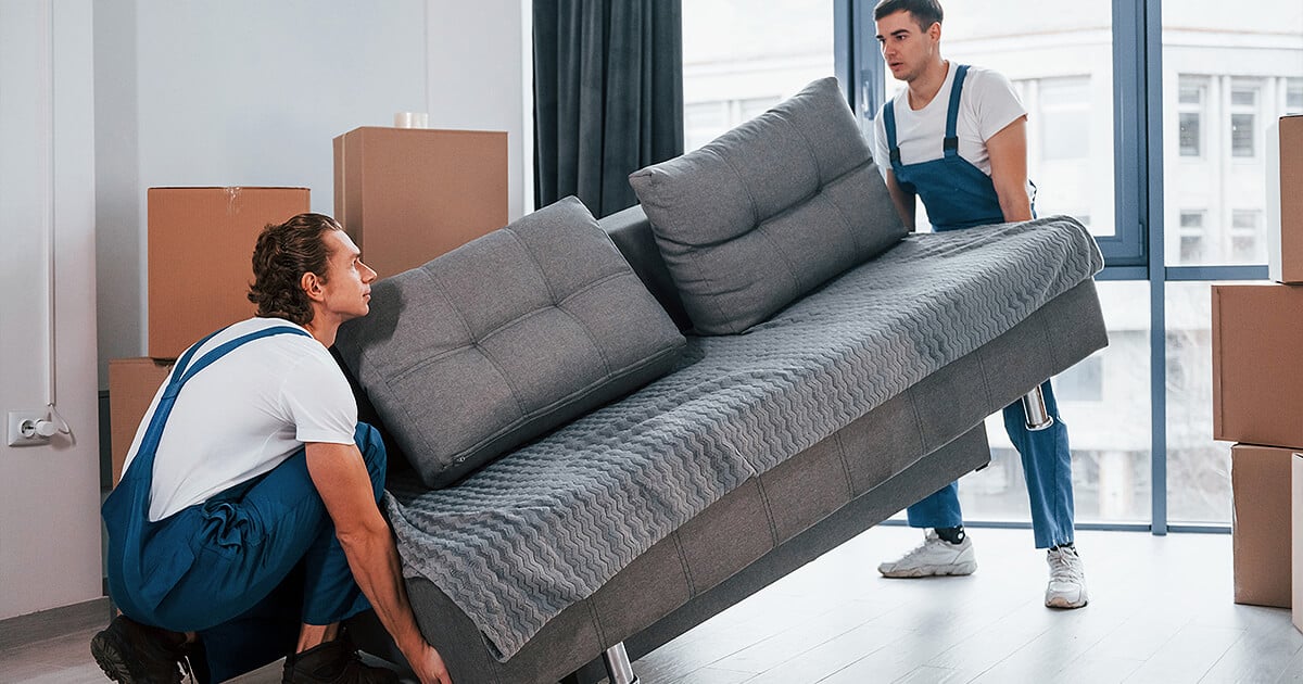 Two removalists lift furniture to move it interstate to new home