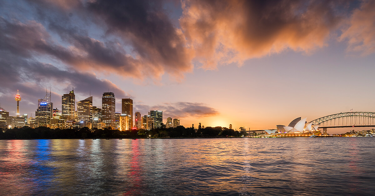 Wide view of Sydney harbour at dawn with lights in the building on