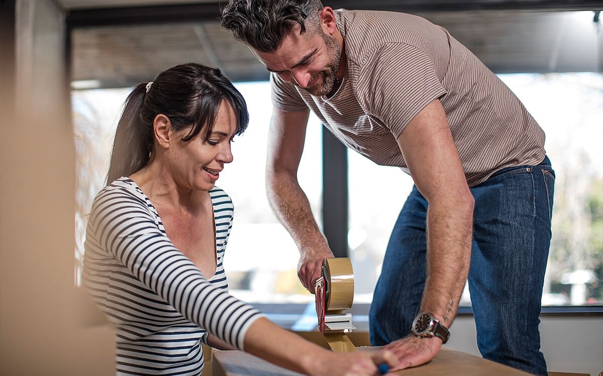 Middle aged couple taping up boxes ready to move home