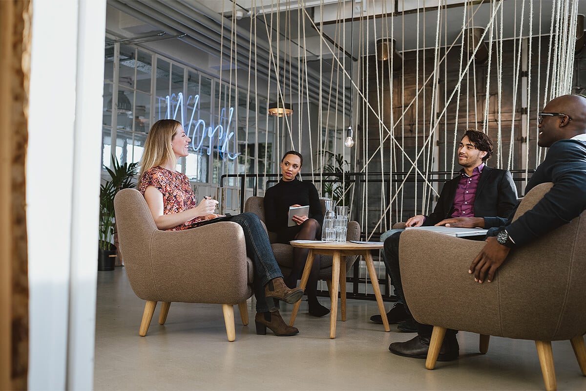 Team meet in comfy chairs in lobby