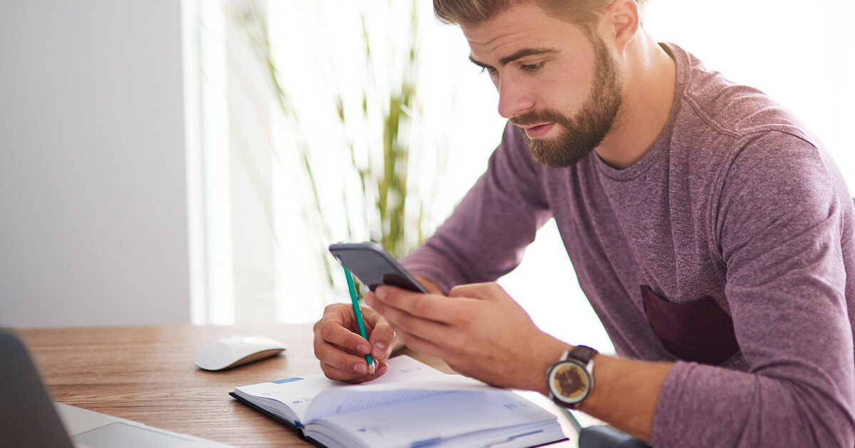 Young man planning with a phone and diary