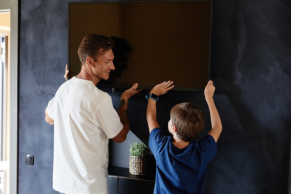 Father and son remove tv from wall before packing