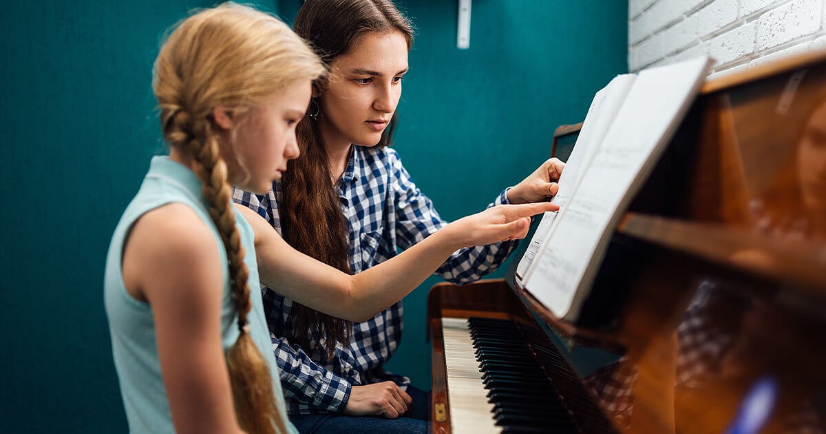 Piano teaches young girl how to play piano on older family piano