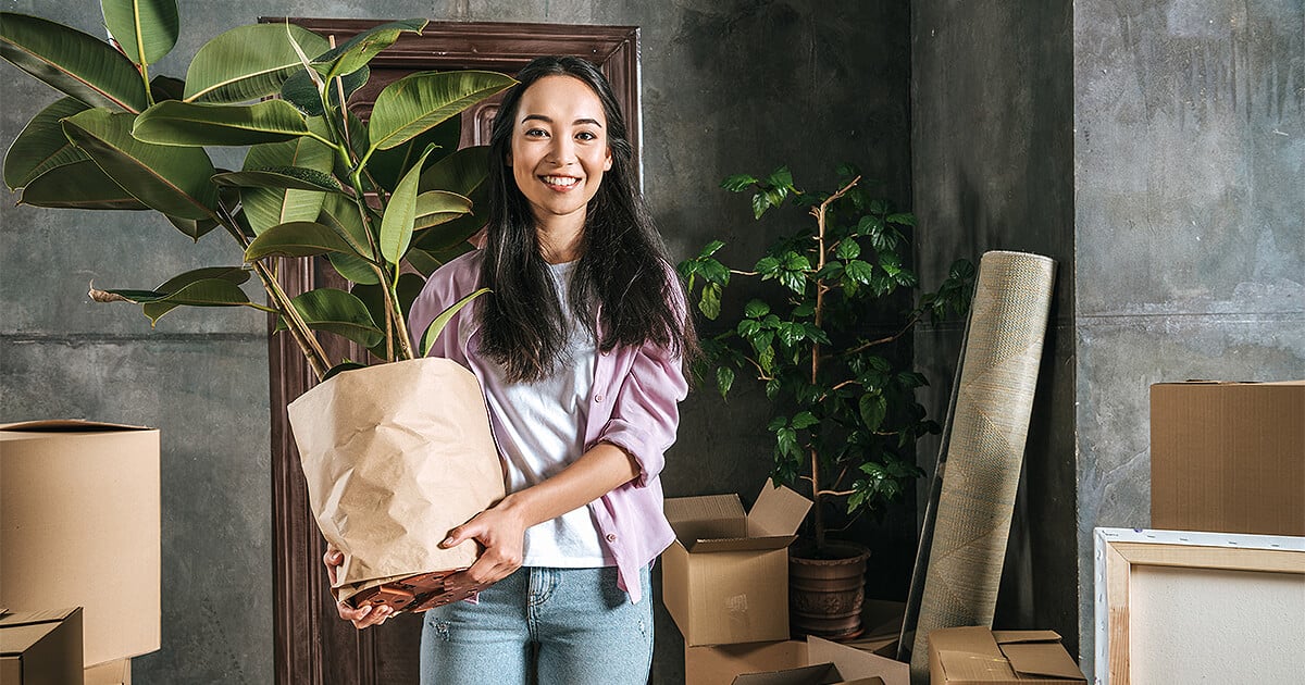 Woman moving large indoor plant into new house after moving home