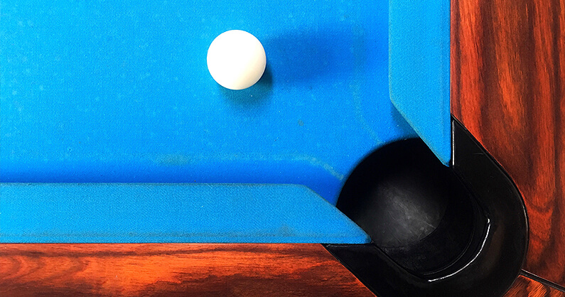 Pool table corner with blue felt and white ball