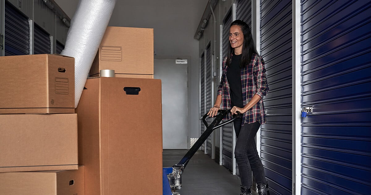 Young woman moves boxes and furniture into self storage unit