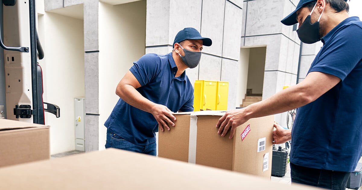 Two interstate removalists moving boxes into the truck