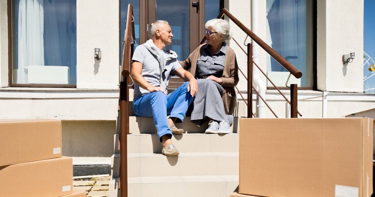 Older family members sitting on stairs moving boxes