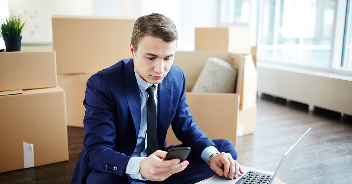 A businessman working while office still has removalist boxes on floor