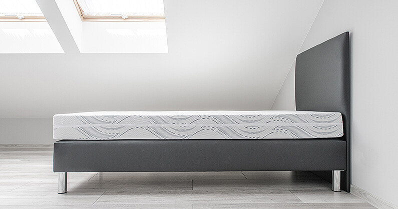 Clean mattress and bed with white walls