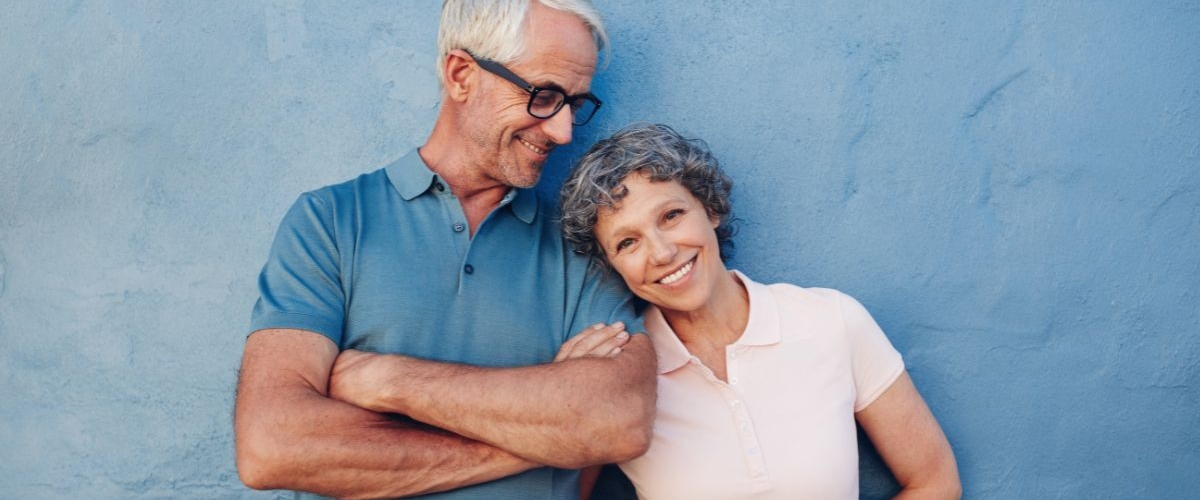 Happy retired couple against blue wall