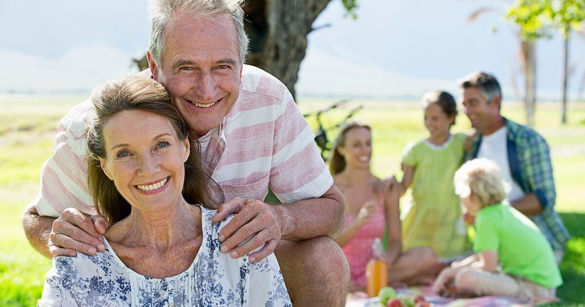 Happy retirement couple with family in background